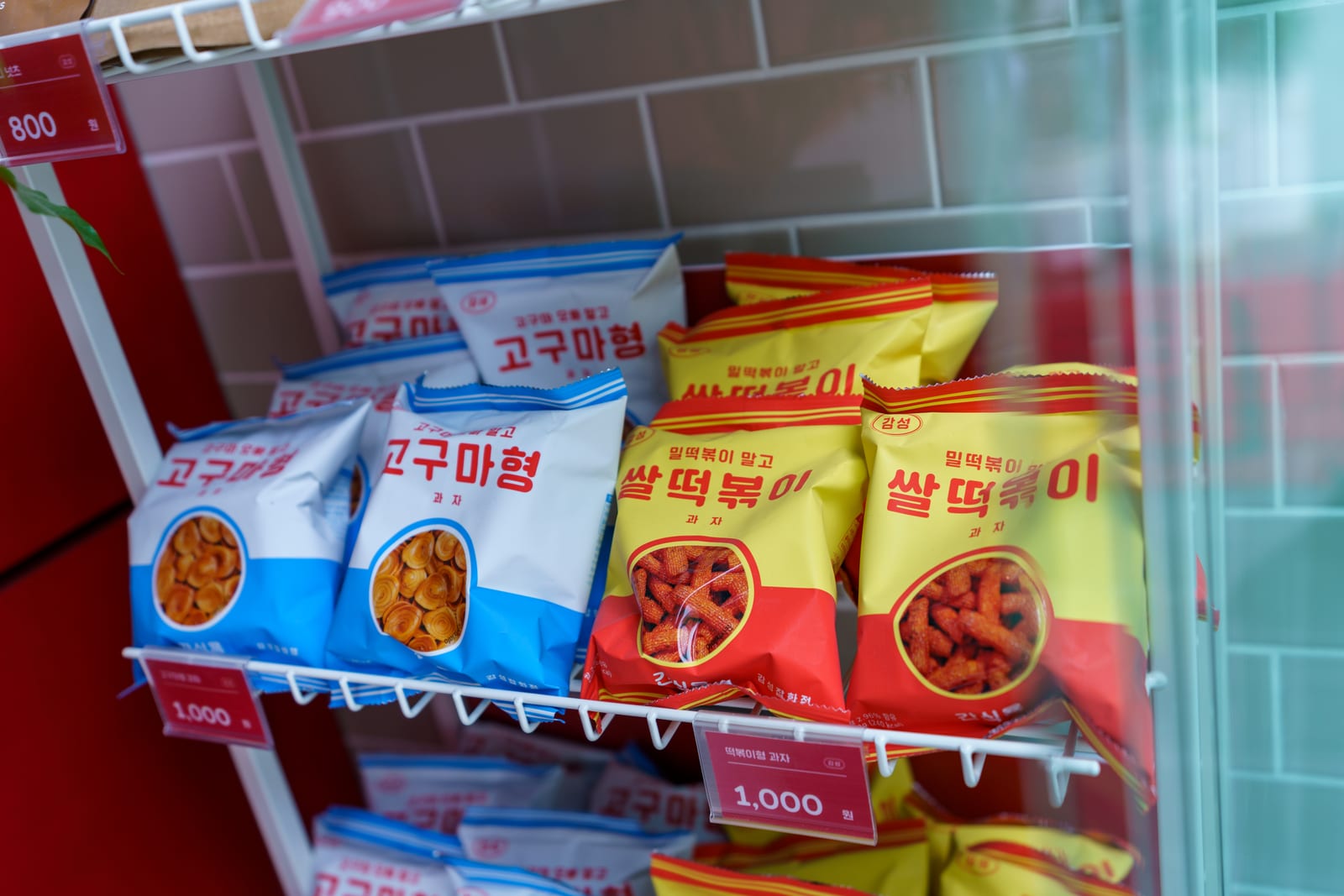 흰 타일 벽 앞 진열대의 스낵 봉지들